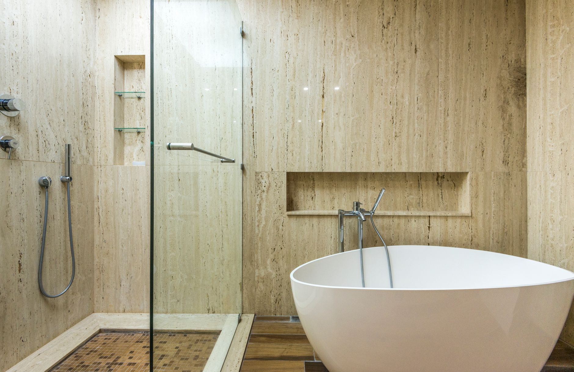Bath — Floor-to-ceiling travertine, a freestanding tub, light from above.