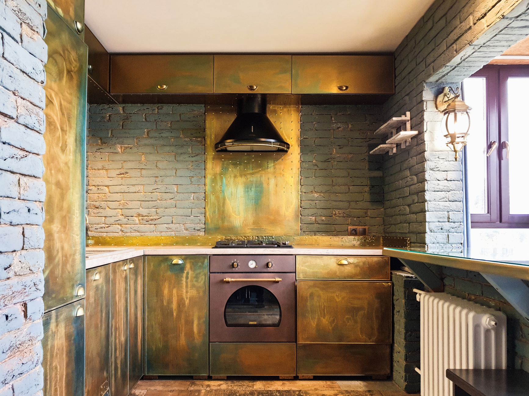 Deep-olive cabinetry against the view. Aged brass, honed stone.
