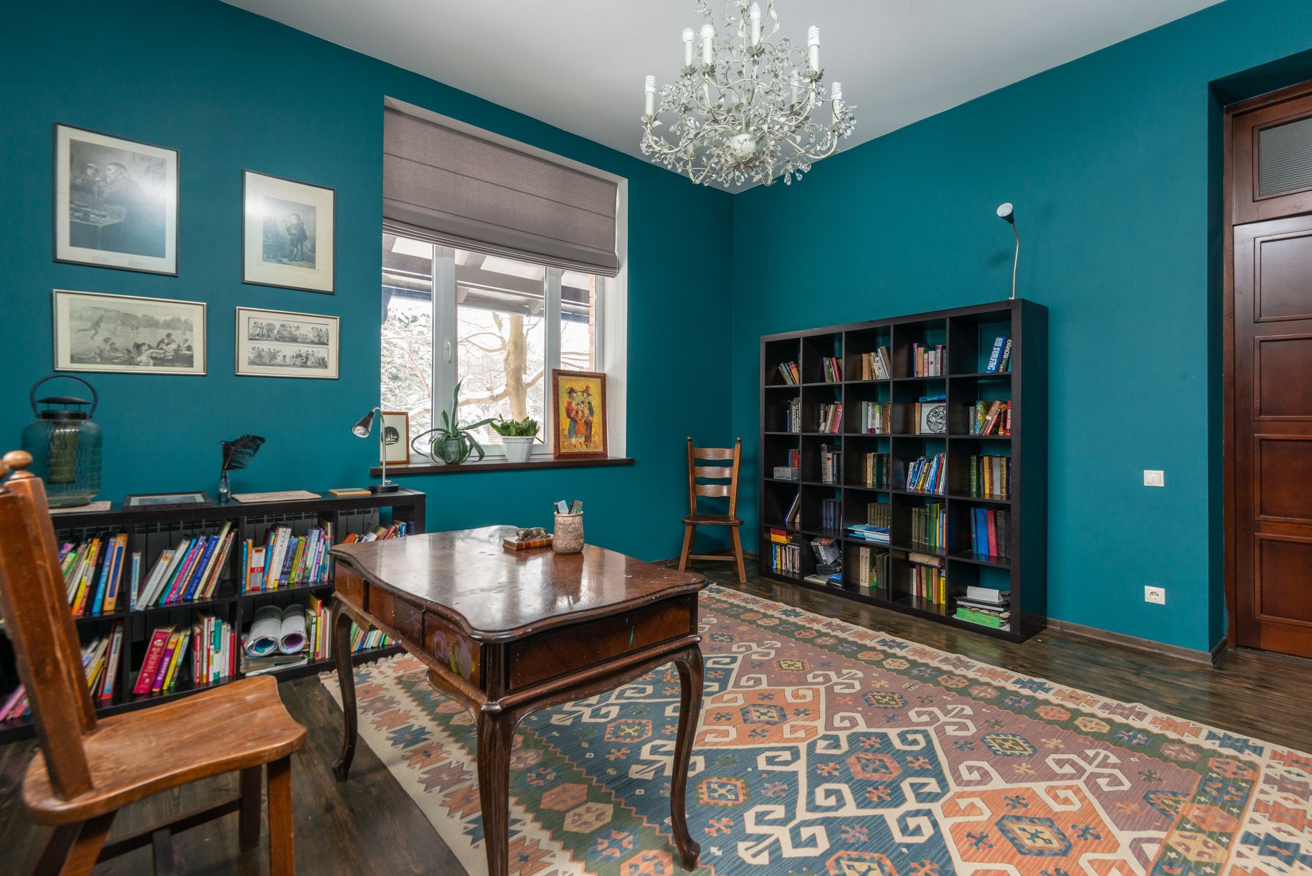 A reading room, rebuilt around the books and a deep-olive settee.